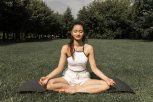 a woman sitting on a mat in a park